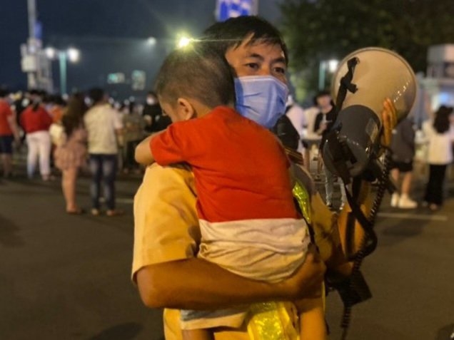 Thiếu tá Đinh Minh Vương bế cháu bé, phát loa tìm mẹ cho bé